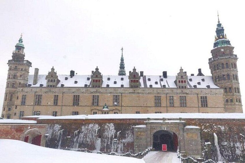 A historic building with multiple towers and a snow-covered roof. 1