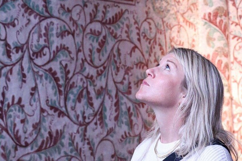 A person standing in front of a wall with a floral pattern. 2