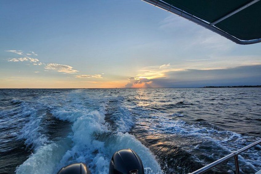 Un bateau naviguant sur l’eau, traversant des vagues, avec un coucher de soleil en arrière-plan et un ciel dégagé. 4
