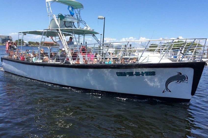 Un bateau orné d’un logo représentant un dauphin, avec des personnes à bord. 3