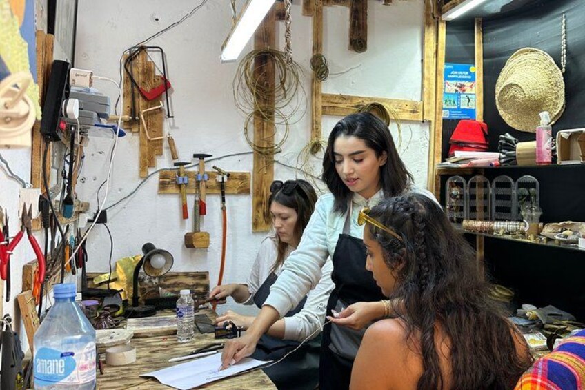 A workshop with tools and materials, including a water bottle and papers on the table. 1