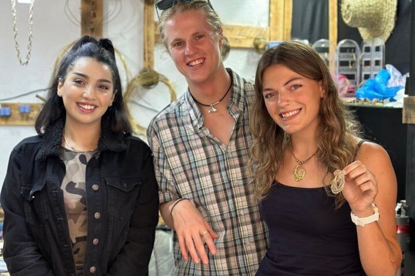 Three people in an indoor setting with a mirror and decorative items in the background. 1