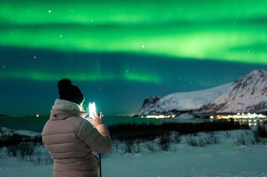 A person taking a photo of the aurora borealis with a smartphone. 3