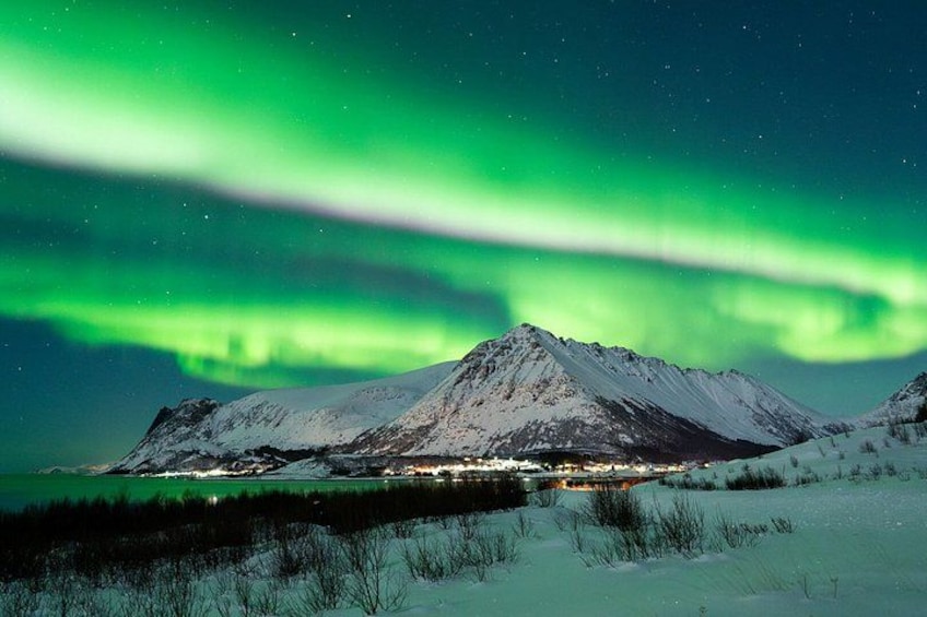 A snow-covered mountain under a green aurora. 2