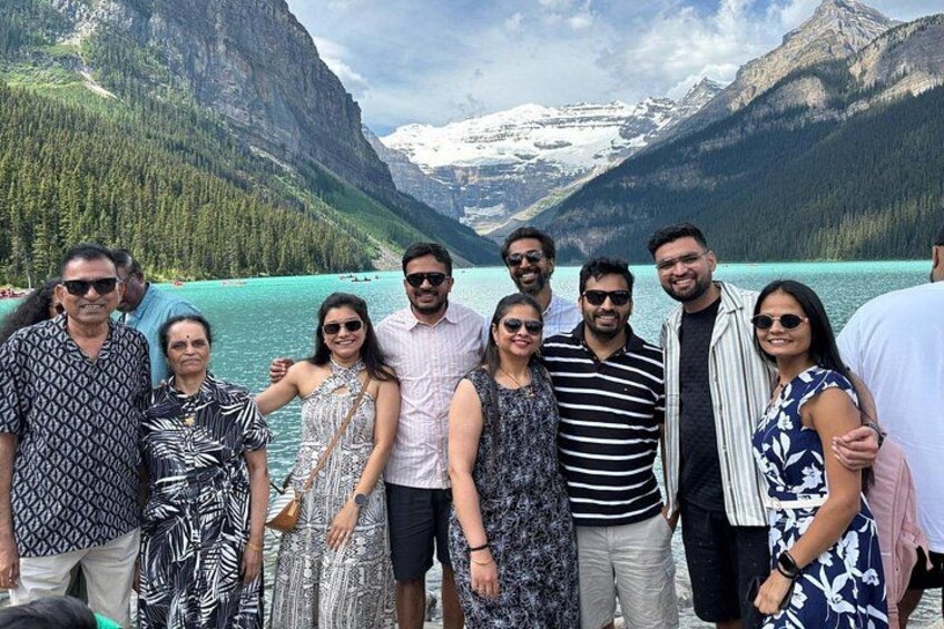 Un groupe de personnes se tient près d’un lac, avec des montagnes en arrière-plan. 4