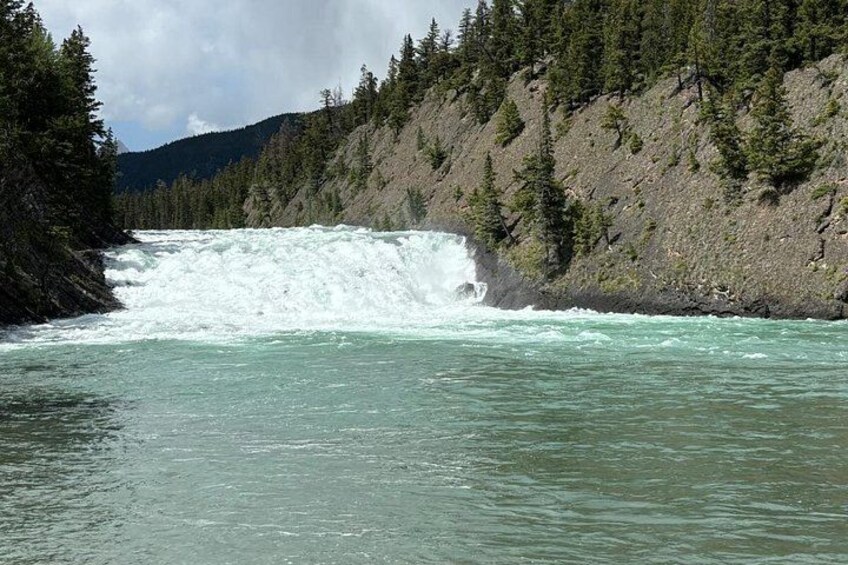 Une rivière avec une cascade, entourée d’une forêt dense et d’un terrain rocheux. 3