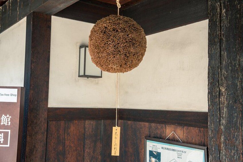 Un intérieur japonais traditionnel agrémenté d’une décoration sphérique suspendue, de poutres en bois et d’un certificat encadré accroché au mur. 2