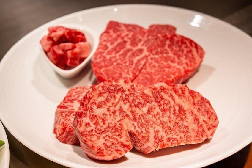 A plate with slices of raw meat and a small bowl of diced meat. 3