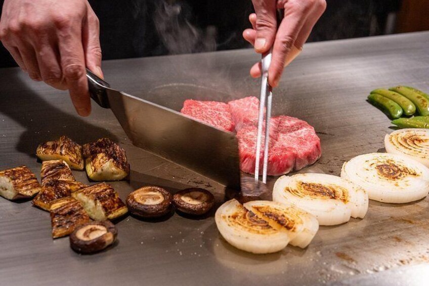 A person grilling various foods on a flat surface. 1