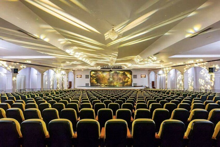Un teatro con filas de asientos, un escenario y una araña. 2