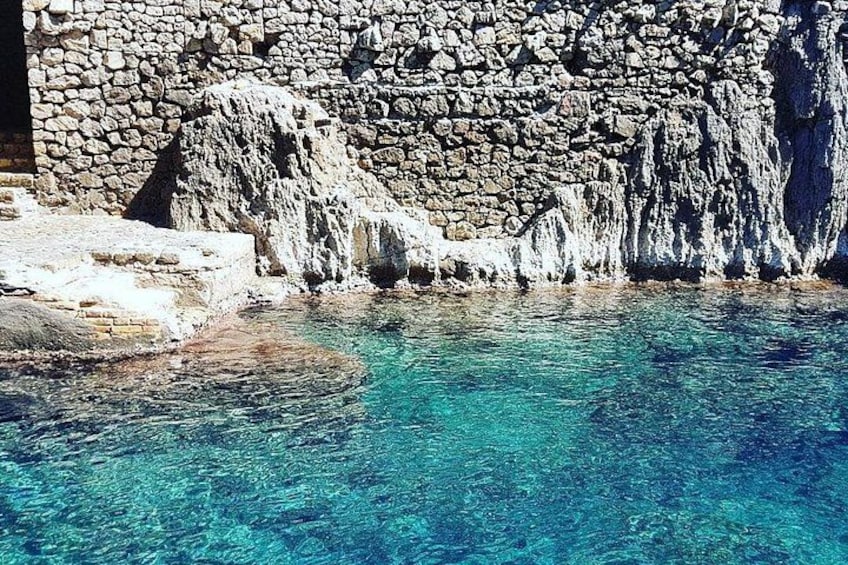 Ein klares, blaues Schwimmbecken mit einer Steinsäule im Hintergrund. 5
