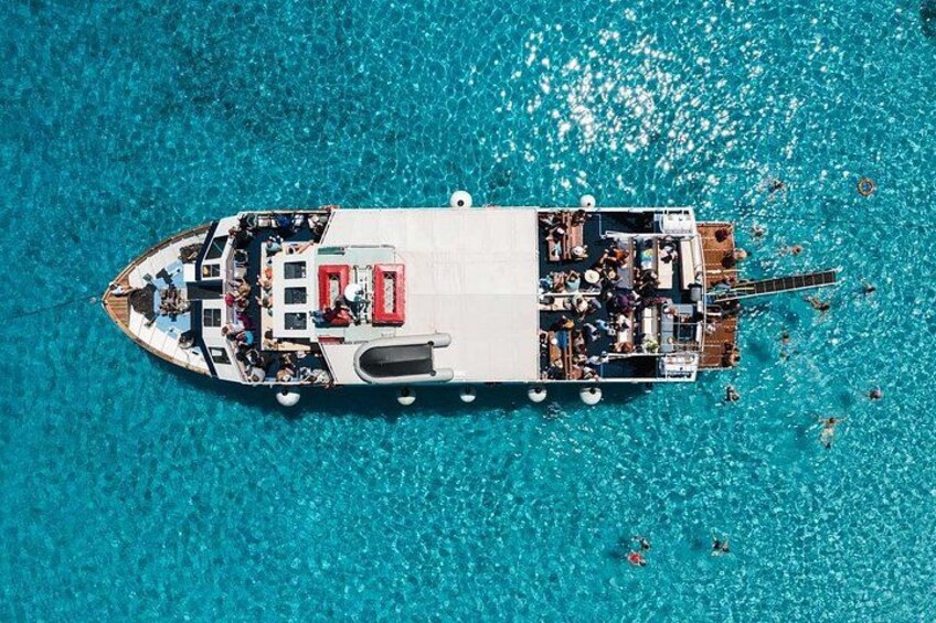 A large boat with people on deck, surrounded by clear turquoise water. 1