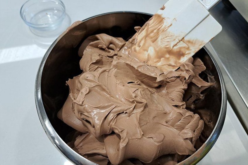 A metal bowl filled with chocolate ice cream being stirred with a spatula. 4