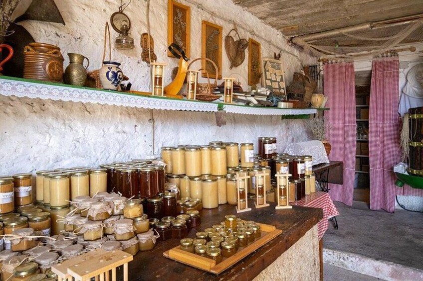 A rustic kitchen with shelves filled with jars and a wooden table with more jars. 5