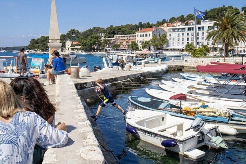 A marina with boats docked, a stone monument, and people near the water. 3