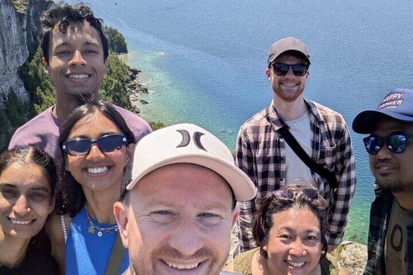 A group of people standing on a cliff overlooking a body of water. 5