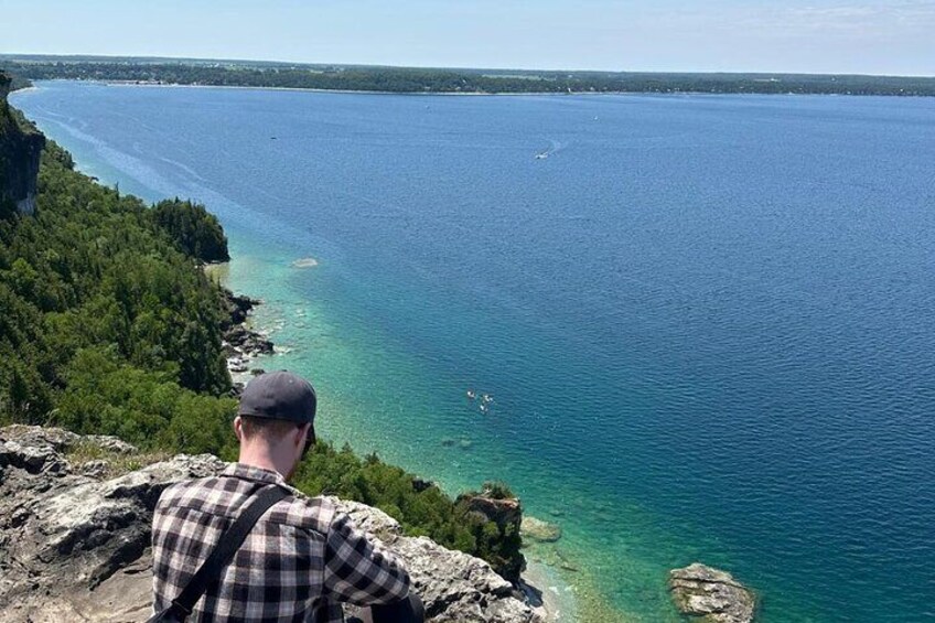 A man overlooking a coastal landscape with clear blue waters and rocky cliffs. 2