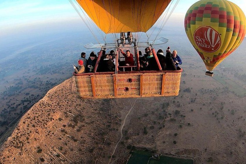 A hot air balloon with passengers, flying over a mountainous landscape. 3