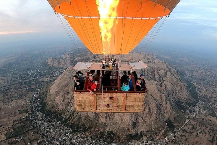 A hot air balloon with passengers over a mountainous landscape. 1