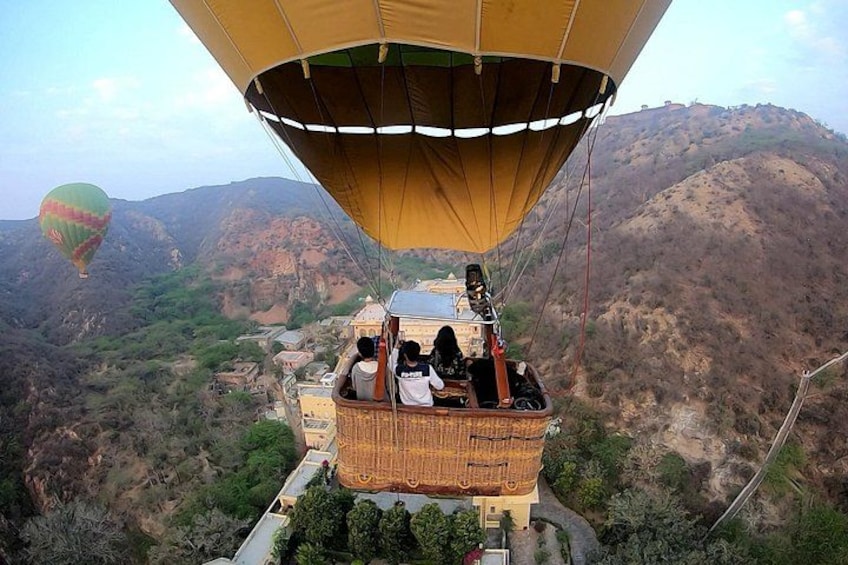 A hot air balloon with passengers over a mountainous landscape. 2