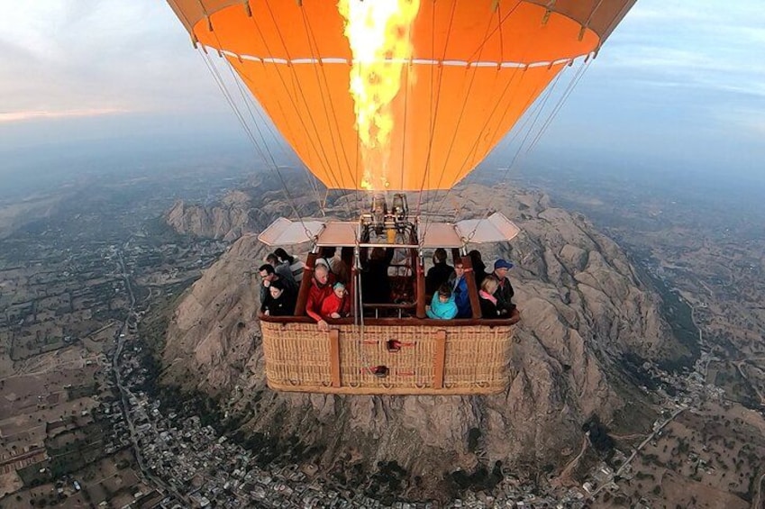 A hot air balloon with passengers over a mountainous landscape. 1