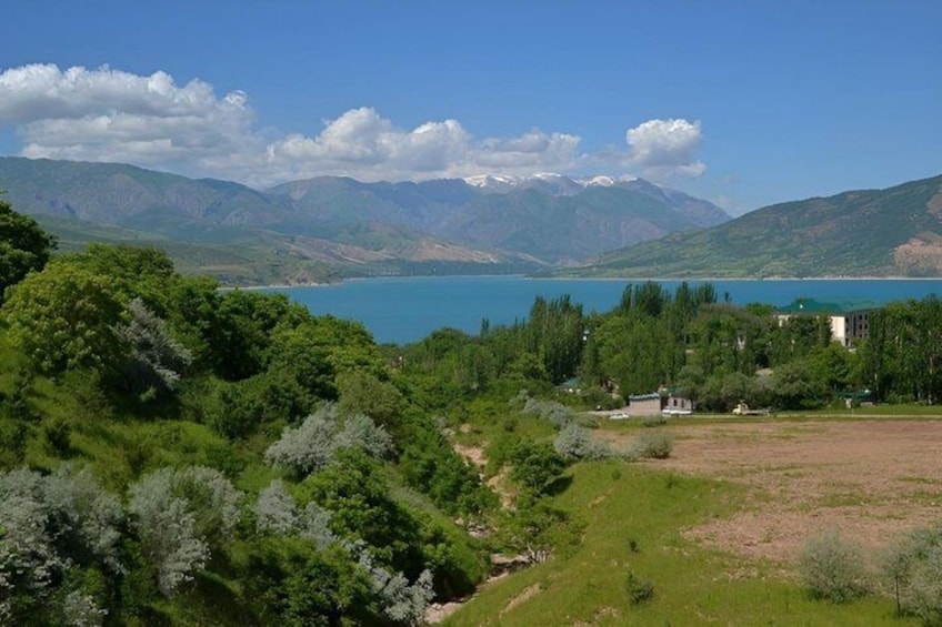 A lake surrounded by mountains, a clear sky, and a forested area with buildings. 3