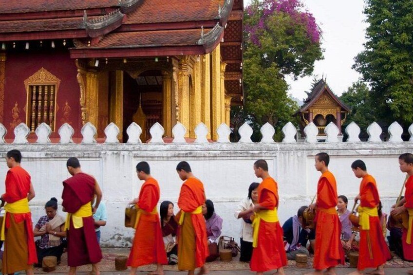Monjes con túnicas anaranjadas realizando un ritual frente a un templo con decoraciones doradas. 2