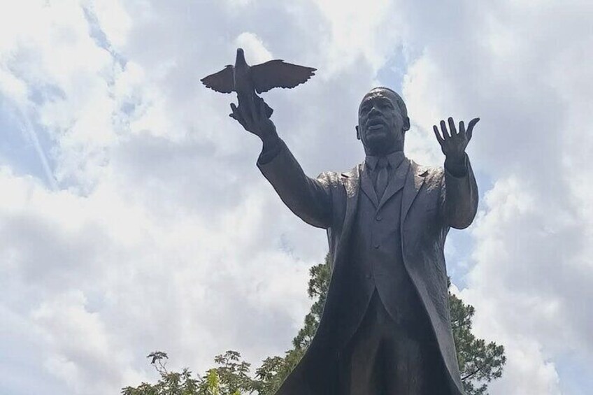 En statue af en mand med udstrakte arme og en fugl i hånden. 1