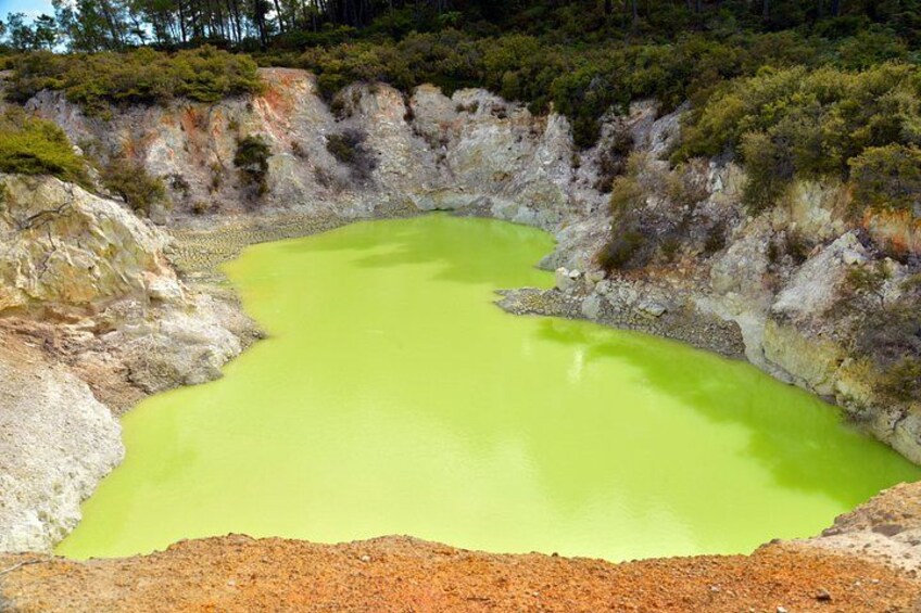 Una piscina mineral verde rodeada de terreno rocoso. 3