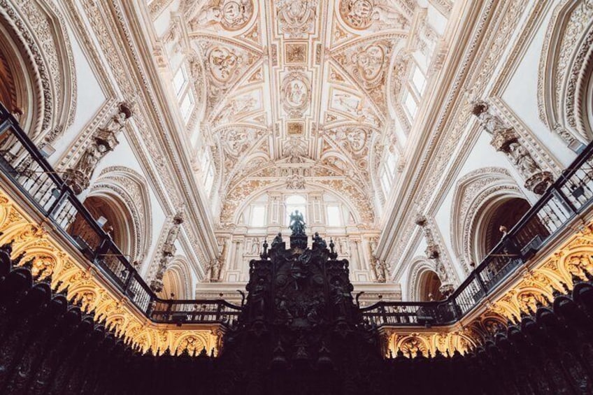 An ornate interior with a high ceiling, intricate ceiling patterns, and a central statue. 4