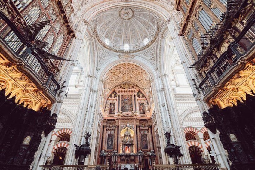 An ornate cathedral interior with a high ceiling, intricate carvings, and a central altar. 3