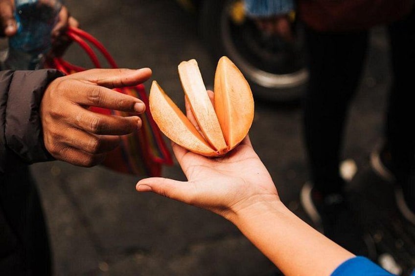 A hand holding a sliced fruit, possibly a papaya, with another hand reaching out to take it. 2
