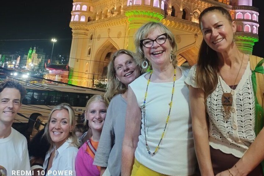 A group of people standing in front of a brightly lit historical building at night. 4
