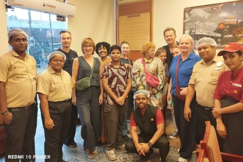 A group of people in a room with a poster on the wall and a window in the background. 2