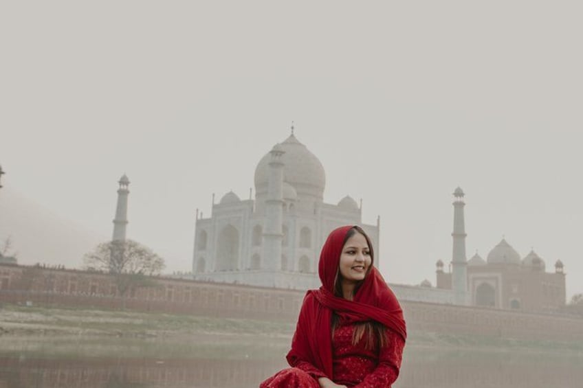 Eine Person in roter Kleidung sitzt vor dem Taj Mahal. 4
