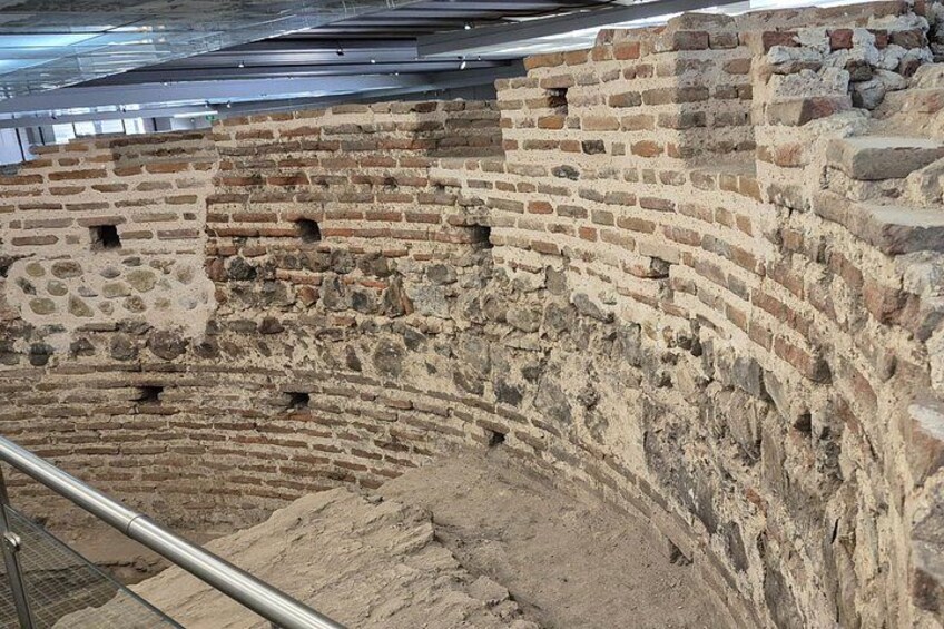 An ancient amphitheater with brick walls and a curved seating area. 5