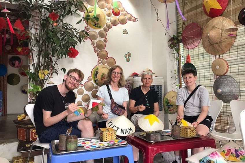 A group of people seated around a table with various items, including a lamp and a tray with objects. 3