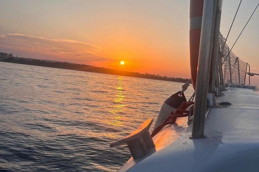A sunset over water, a boat, and a person sitting on the deck. 4