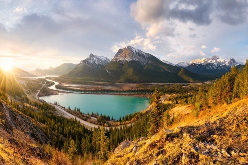 Un paisaje montañoso con un lago, una carretera serpenteante y una zona boscosa. 5