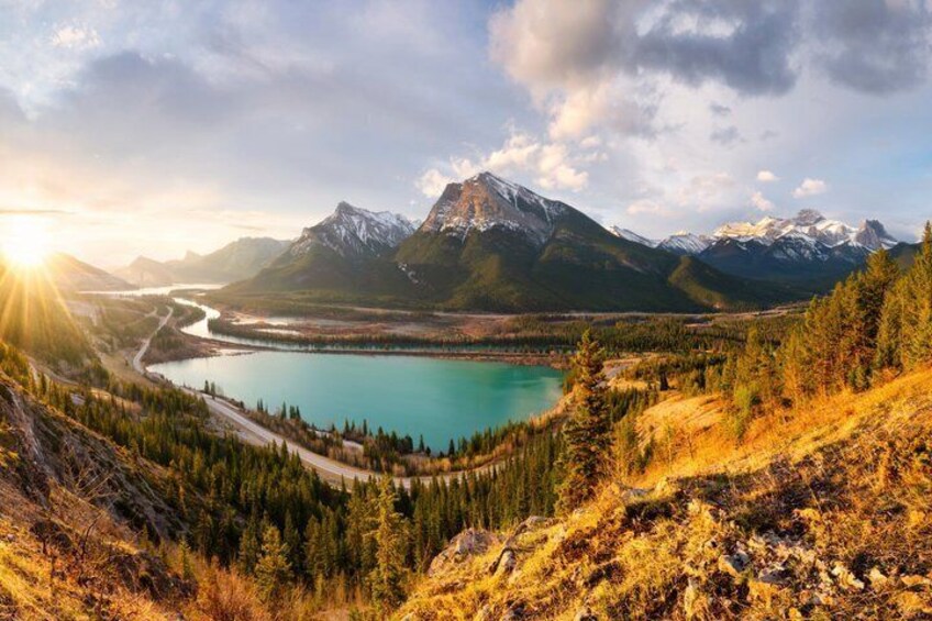 A mountain landscape with a lake, a winding road, and a forested area. 3