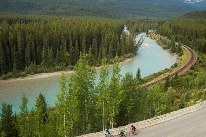 Un río serpentea a través de un bosque, una vía ferroviaria y ciclistas en una carretera. 2