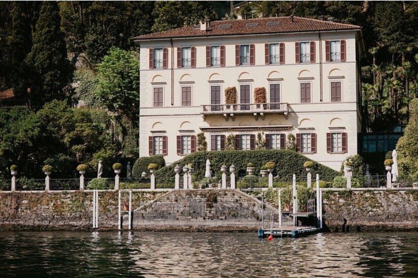 A large, multi-story building with a symmetrical facade, surrounded by a body of water and lush greenery. 3