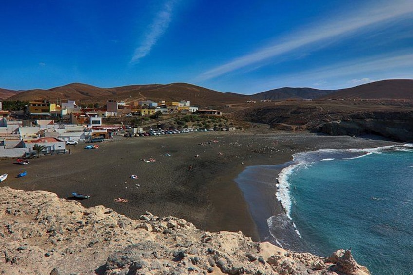 A coastal town with buildings, a beach, and mountains. 2