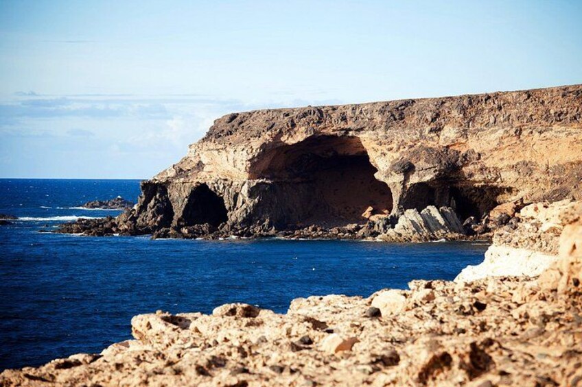A rocky coastline with a prominent cliff and a cave-like formation. 4