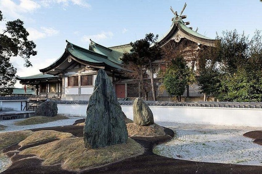 A traditional Japanese building with a curved roof, surrounded by rocks and gravel. 5