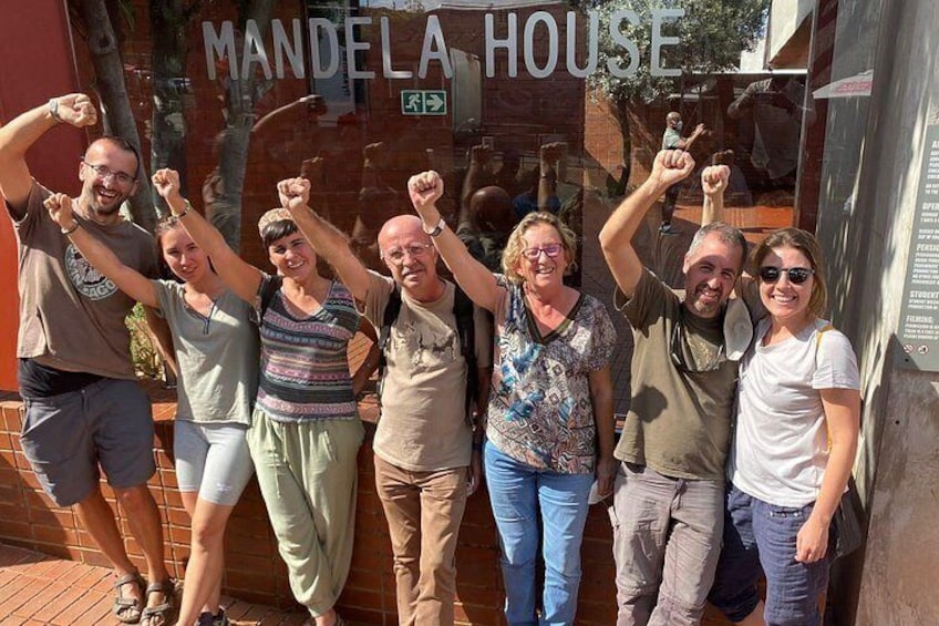 A group of people posing in front of a building with a sign that reads 'MANDELA HOUSE'. 2