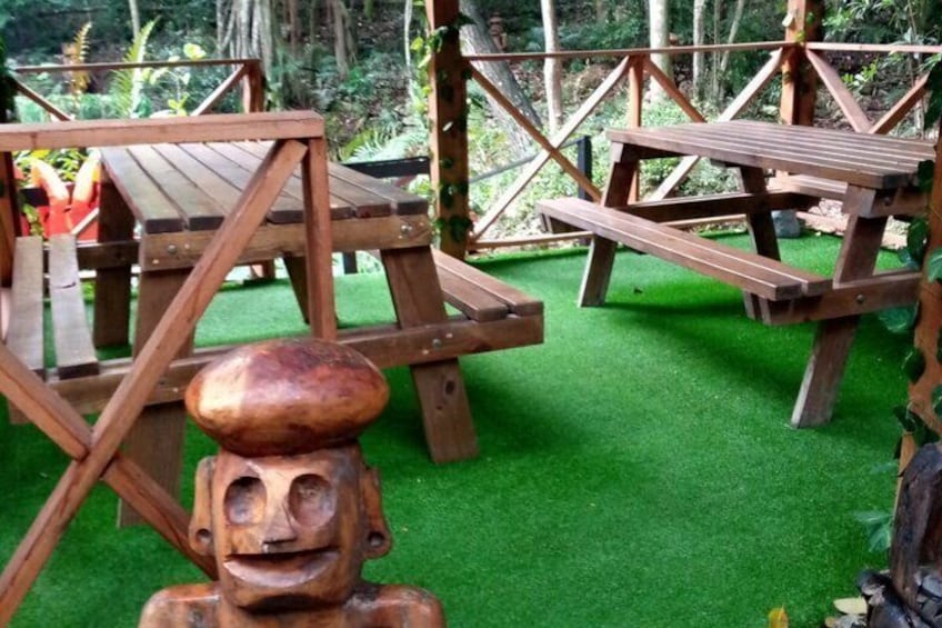 A wooden picnic area with benches and a sculpture on artificial grass. 2