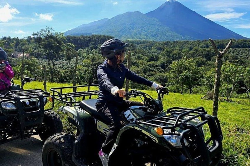 A person riding an ATV on a road with a mountain in the background. 3