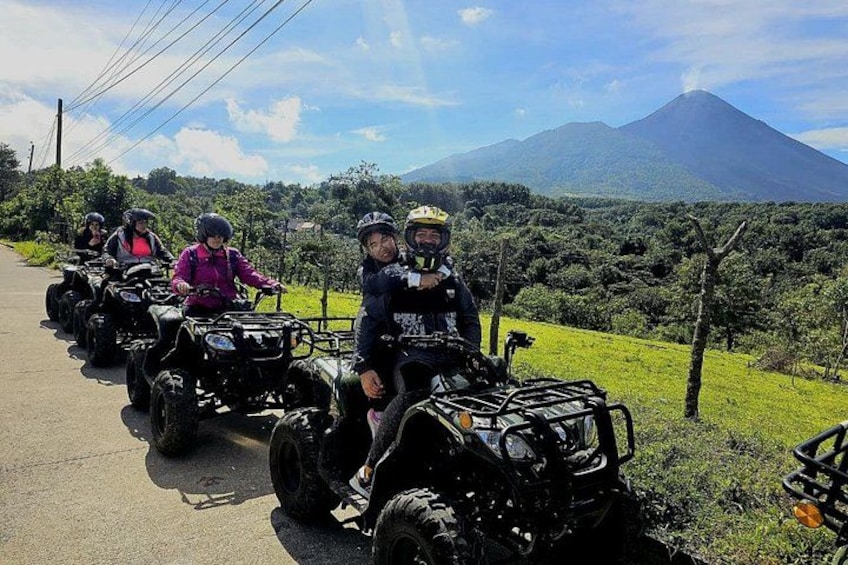 A group of people on ATVs on a road with a mountain in the background. 4