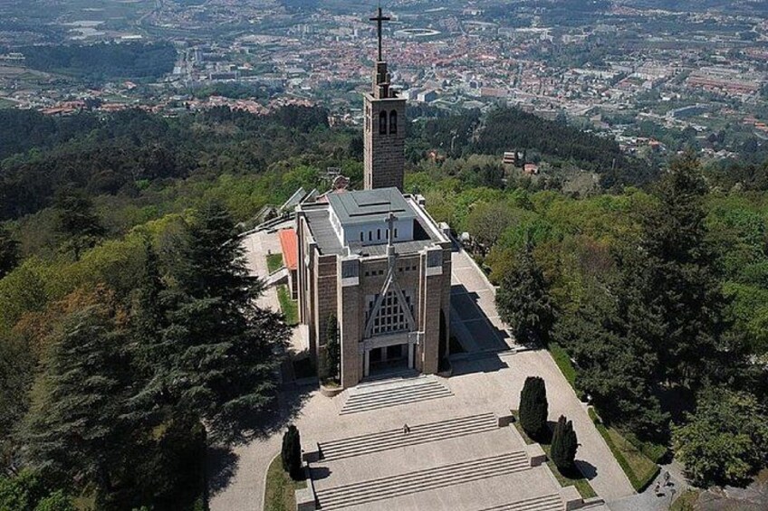 A church with a tall bell tower, surrounded by trees and a paved area in front. 4